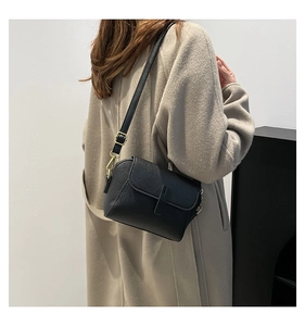 Side view of a vintage black leather square crossbody bag with textured litchi pattern