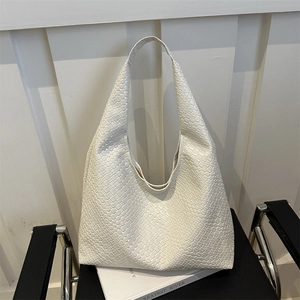 White vintage embossed hobo tote bag for women shown on a stylish modern chair