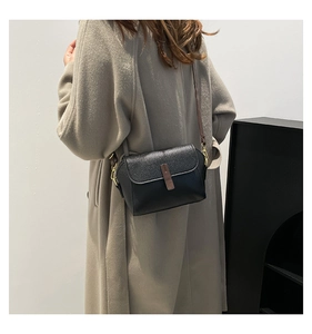 Gros plan détaillé du cuir grainé noir et de la boucle dorée du sac à bandoulière