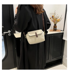 Vue macro du sac à bandoulière en cuir crème avec sangle brune et texture grainée