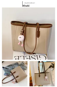 Detail view of khaki minimalist tote bag with dark brown trim and pink plush charm
