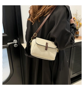 Detail of creamy white crossbody bag showing soft lychee texture and brown strap