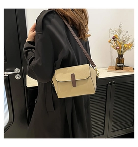 Détail d'un sac bandoulière en cuir beige grainé avec une fine lanière marron chic
