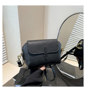 Détail du sac bandoulière en cuir grainé noir avec finitions dorées et rabat aimanté