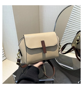 Gros plan sur le cuir beige grainé et les détails de la bandoulière marron du sac