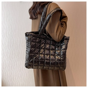 Rear view of model wearing black quilted nylon puffer tote bag with glossy finish