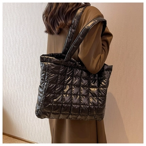 Detail showing the square quilted texture and puffer material of the black tote bag