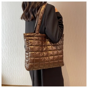 Detail of dark brown quilted puffer tote bag shown on model for size perspective