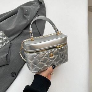 Silver quilted crossbody bag with gold camellia logo and chain strap held by model