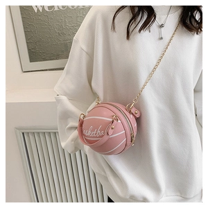 Pink basketball shaped crossbody bag with gold chain strap shown on model outfit