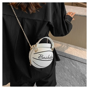 Detail shot of a white basketball-shaped chain bag worn as a crossbody by a model