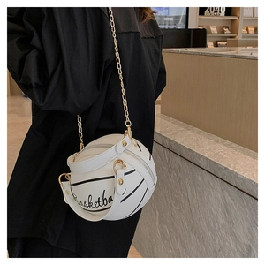 Detail of white basketball shaped crossbody bag with gold chain strap on model