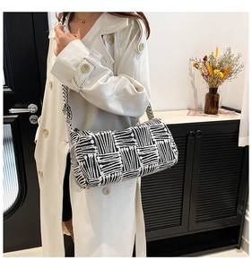 Detail of a black and white striped cylindrical shoulder bag worn with a white coat