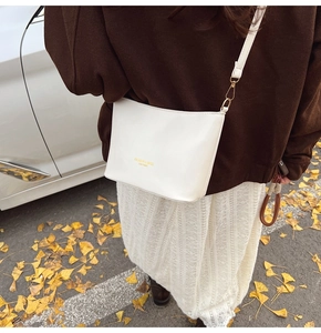 Detail einer weißen Leder-Eimertasche mit Goldaufdruck in einer Street-Lifestyle-Szene