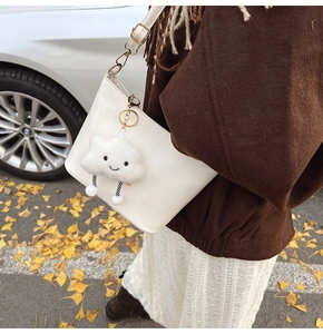 Detail of white leather shoulder bag with cute plush cloud charm and golden hardware