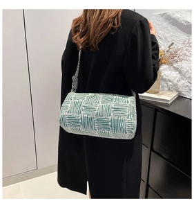 Detail of green and white striped cylindrical bag with a wide checkered canvas strap