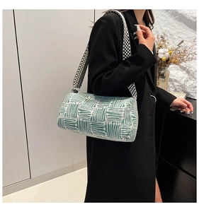 Detail of green and white knit cylinder bag featuring wide polka dot strap and metal hardware