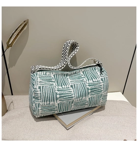 Detail of green and white geometric knit cylinder bag with woven pattern and shoulder strap