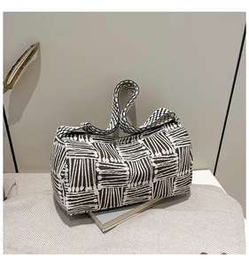 Detail of black and white woven cylindrical bag with geometric patterns and a wide strap