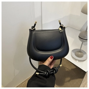 Détail du sac à main noir mat avec bandoulière nouée et fermeture éclair en métal doré