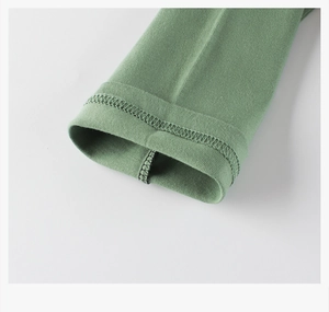 Gros plan des ourlets à double aiguille sur un t-shirt vert à manches longues pour enfant