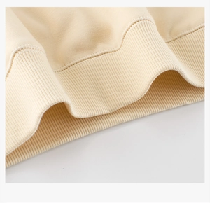 Detailed close-up of ribbed cuffs and stitching on beige fleece-lined sweatshirt
