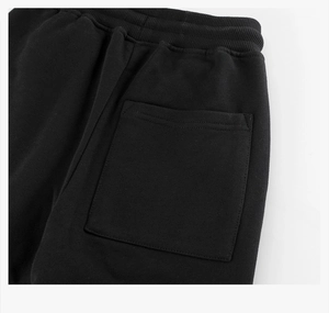 Detail of wide elastic ribbed waistband and square back pocket on black cotton joggers