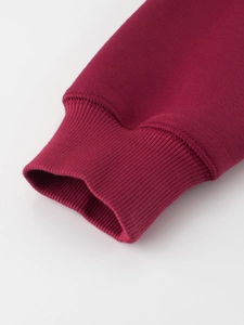 Detail of ribbed cuffs on dark red crewneck sweatshirt in premium thick fabric