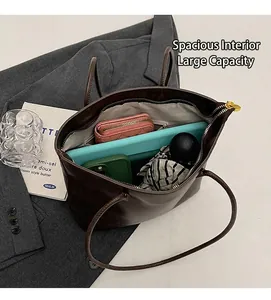 Draufsicht auf den geräumigen Innenraum der braunen Ledertasche mit Tablet und Schirm