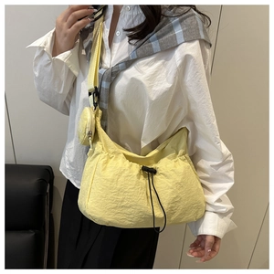 Detail of light yellow nylon drawstring crossbody bag with round charm and wide strap