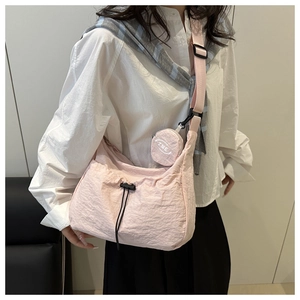 Detail of pink pleated crossbody bag featuring black drawstring and round coin purse