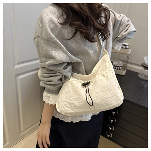 Detailed side view of white wrinkled nylon shoulder bag with adjustable black drawstring