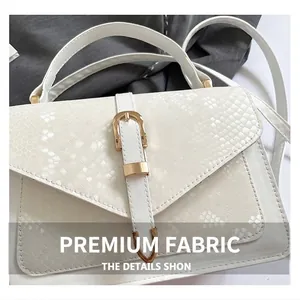 Gros plan sur un sac blanc à bandoulière avec texture serpent et boucle dorée