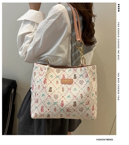 Detail of quilted cream tote bag featuring colorful cartoon prints and pink leather strap
