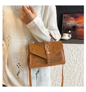 Close-up of brown faux leather shoulder bag featuring snakeskin texture and belt buckle