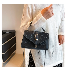 Detail of black snake pattern leather handbag with gold U-shaped buckle and strap