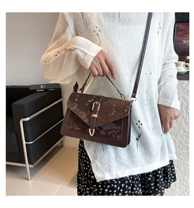 Detail of luxury snake-print handbag with gold buckle clasp and dark brown leather texture