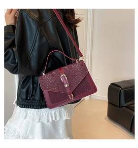 Detail of burgundy snakeskin patterned crossbody bag worn with casual leather jacket