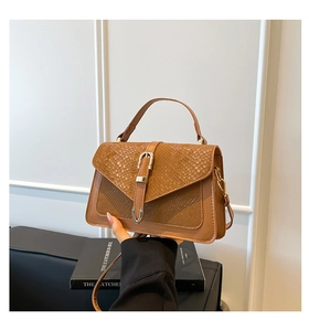 Detail of vintage brown handbag featuring snake pattern texture and metal buckle decor