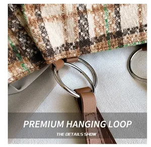 Detail of tweed check bag with silver metal rings and brown leather strap stitching