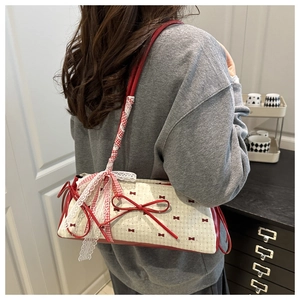 Detail of canvas underarm bag featuring red bow prints and decorative lace strap