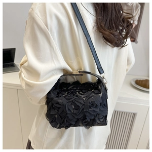Detail of 3D mesh rose flowers on black shoulder bag shown in a lifestyle scene