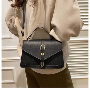 Close-up of black lychee grain leather crossbody bag with golden horseshoe buckle details