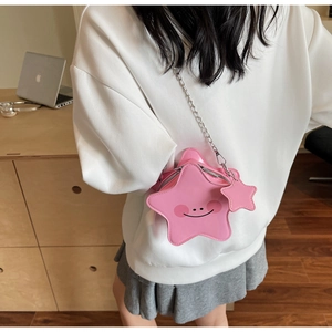 Close-up of pink star-shaped crossbody bag with silver chain and cute blush face design