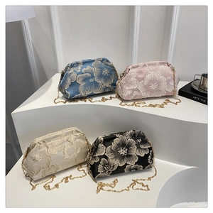 Detail of four floral embroidery mini bags with gold chains on white stairs stand