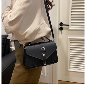 Close-up of black pebble leather handbag with gold horsebit hardware and slim strap