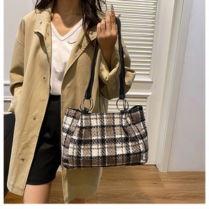 Detail of plaid tote bag showing textured weave, slim handles, and silver ring connectors