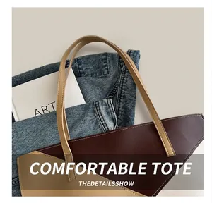 Close-up of two-tone leather tote bag with fine stitching and slim brown handles
