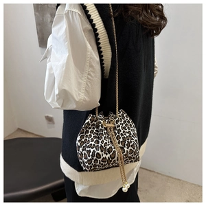 Detalle del bolso de cubo de leopardo con cadena dorada y dije de perla al hombro