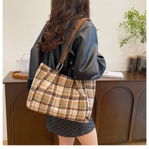 Detail of plaid wool tote bag featuring brown leather strap and metal ring attachment